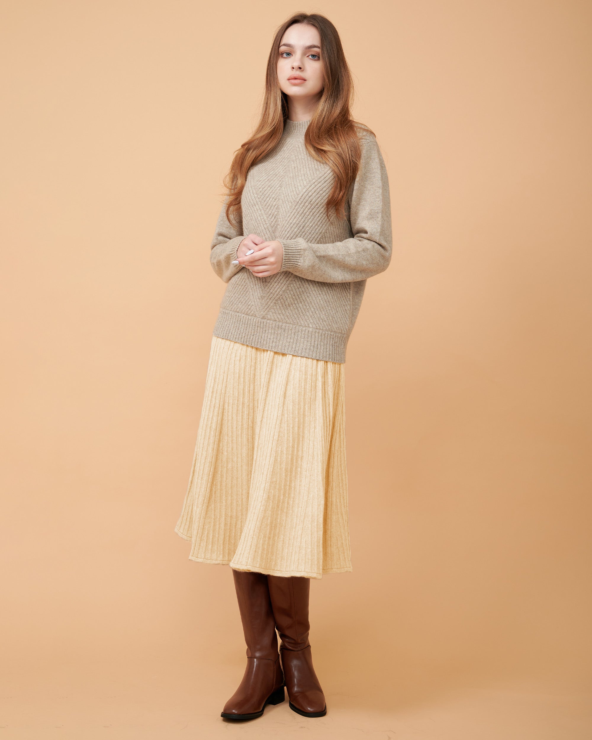 A woman wearing a creame cashmere midi skirt with pleats and a Cashmere sweater
