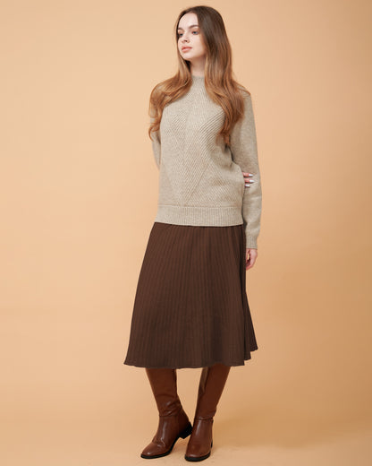 A woman wearing a dark brown cashmere midi skirt with pleats and a Cashmere sweater